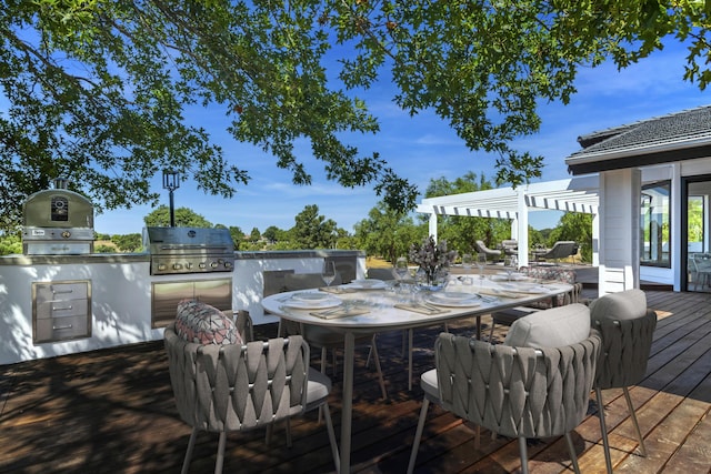 wooden deck featuring an outdoor kitchen, a grill, and a pergola