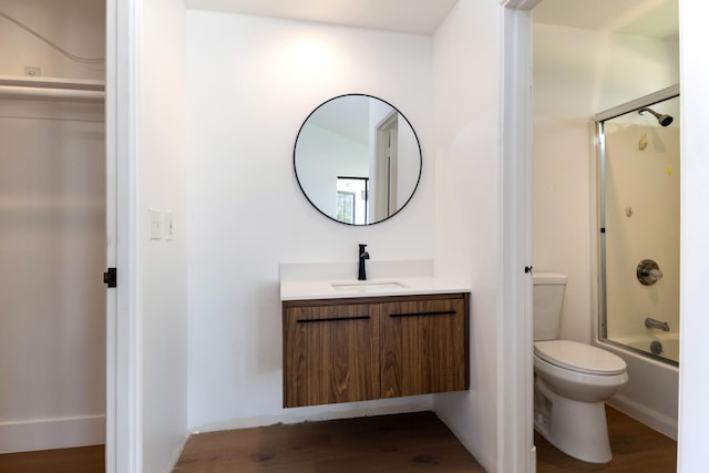 full bathroom with vanity, hardwood / wood-style flooring, enclosed tub / shower combo, and toilet