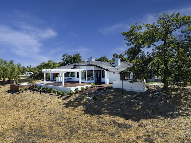 back of house featuring a wooden deck and a patio