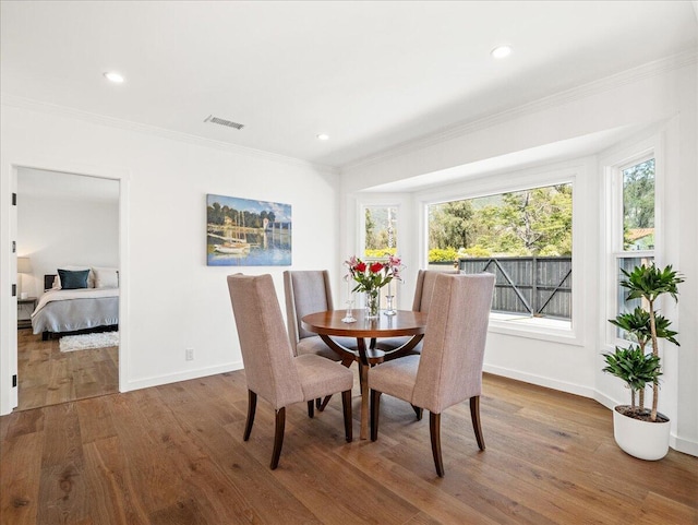 dining space with baseboards, visible vents, wood finished floors, and ornamental molding