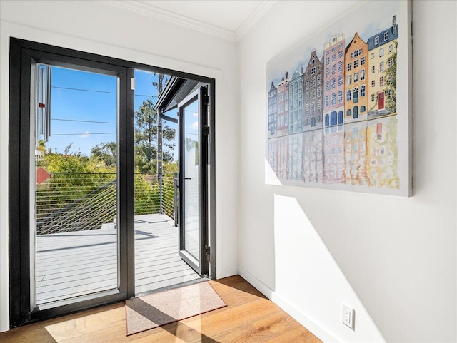 doorway to outside featuring ornamental molding, wood finished floors, and baseboards