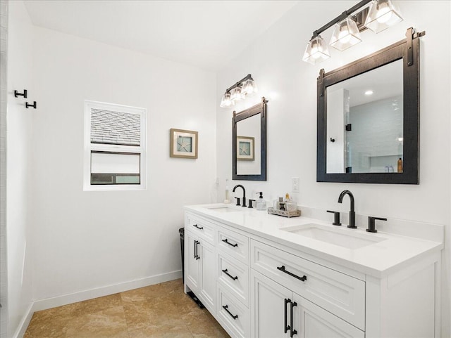 bathroom with double vanity, a shower, a sink, and baseboards