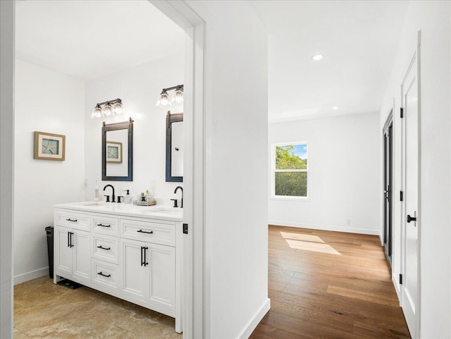 bathroom featuring double vanity, a sink, baseboards, and wood finished floors