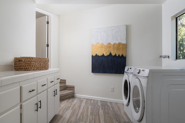 laundry room with cabinets, independent washer and dryer, and light hardwood / wood-style flooring