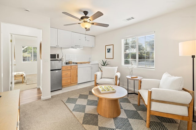 sitting room featuring light carpet, sink, and ceiling fan