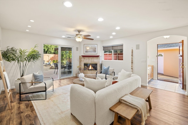 living room with ceiling fan, plenty of natural light, a fireplace, and light hardwood / wood-style floors