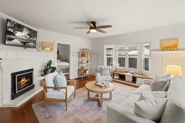 living room with a fireplace, wood-type flooring, and ceiling fan