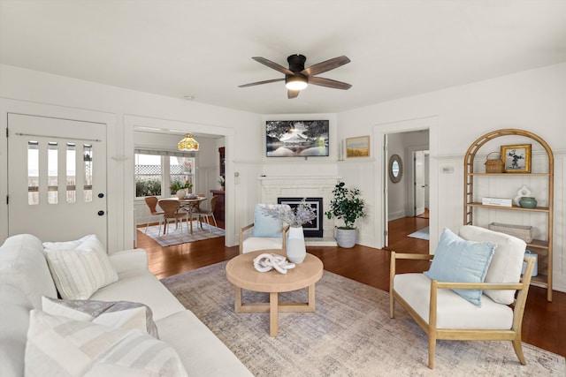 living room featuring ceiling fan, hardwood / wood-style floors, and a brick fireplace