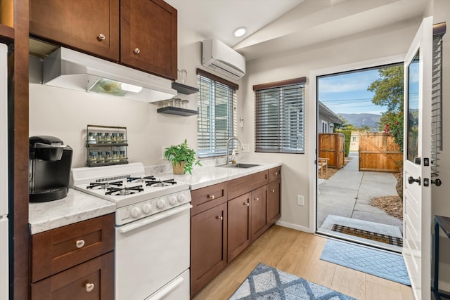 kitchen with sink, a wealth of natural light, a wall unit AC, and white gas range oven