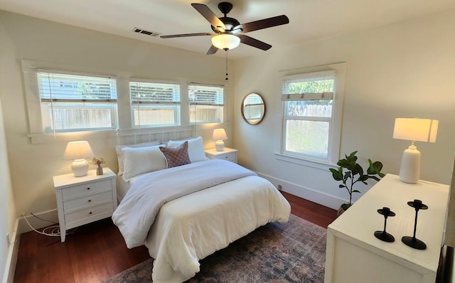 bedroom with a ceiling fan, dark wood finished floors, visible vents, and baseboards