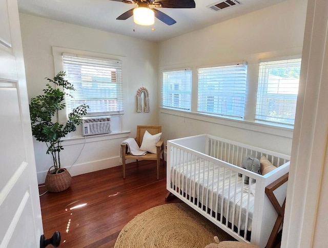 bedroom with cooling unit, visible vents, ceiling fan, and wood finished floors