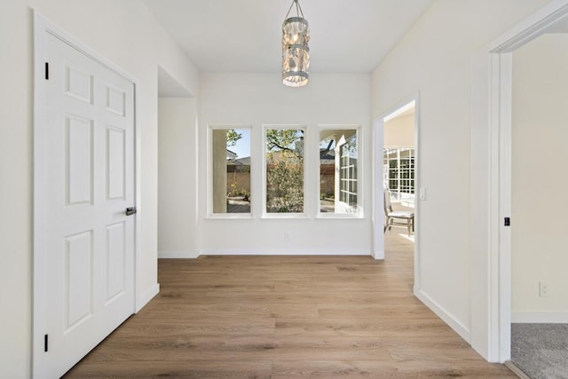 hallway with an inviting chandelier and light hardwood / wood-style floors