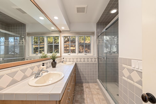 bathroom featuring tile walls, vanity, tile patterned flooring, and a shower with door