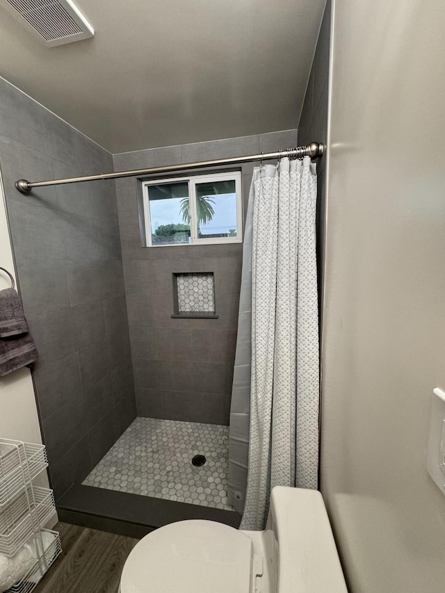 bathroom featuring toilet, hardwood / wood-style floors, and walk in shower