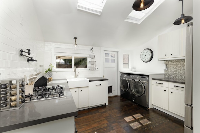 kitchen featuring dark wood-type flooring, sink, separate washer and dryer, vaulted ceiling with skylight, and white cabinets