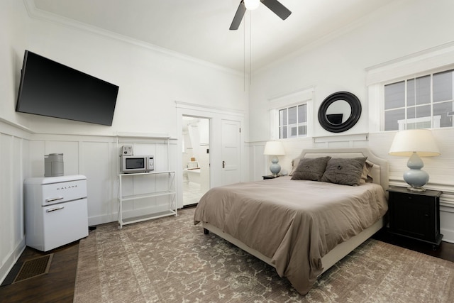 bedroom featuring crown molding, ensuite bath, ceiling fan, and dark wood-type flooring