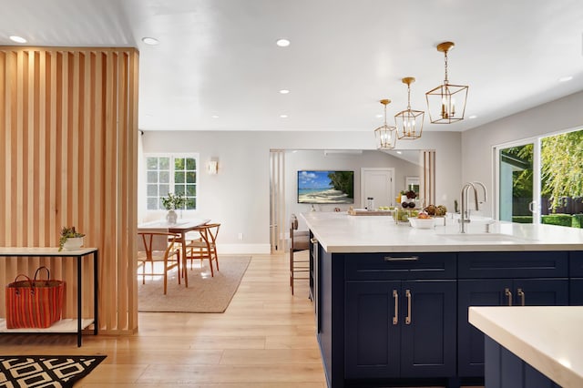 kitchen with a center island with sink, sink, a wealth of natural light, and light wood-type flooring