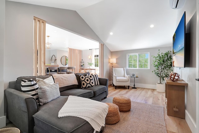 living room with lofted ceiling, light hardwood / wood-style floors, and an AC wall unit