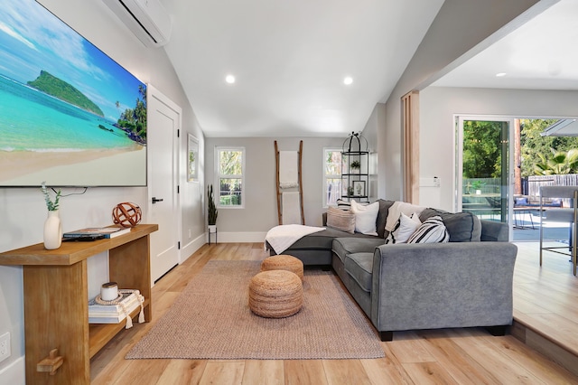 living room with vaulted ceiling, a wall unit AC, and light wood-type flooring