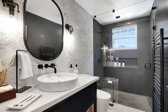 bathroom with radiator heating unit, a shower with shower door, tasteful backsplash, vanity, and toilet