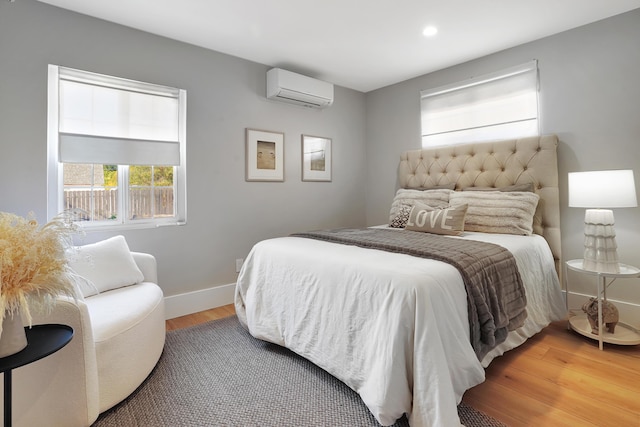 bedroom featuring hardwood / wood-style flooring and a wall mounted AC