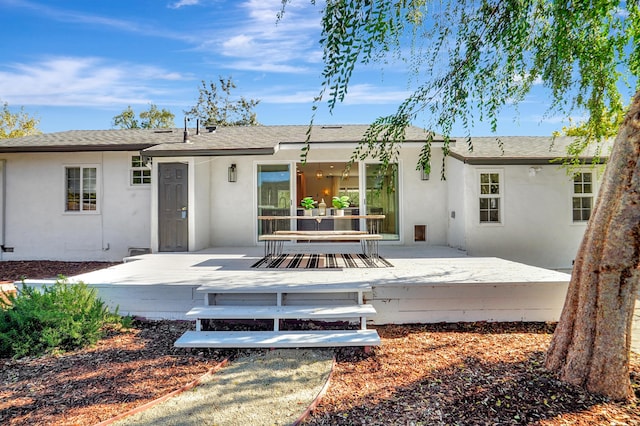 rear view of house featuring a wooden deck and a patio area