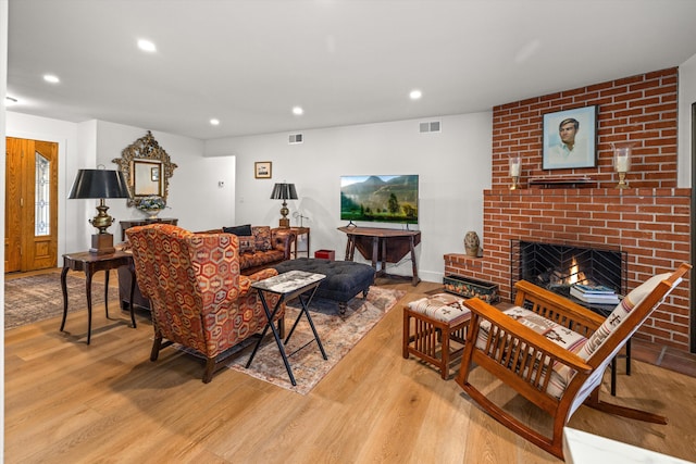 living room with a brick fireplace and light wood-type flooring