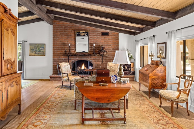 living room featuring a fireplace, lofted ceiling with beams, wooden ceiling, and light wood-type flooring