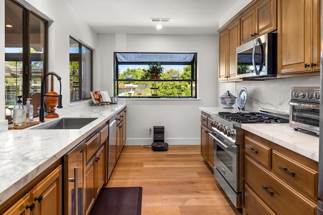 kitchen featuring tasteful backsplash, appliances with stainless steel finishes, sink, and light stone counters