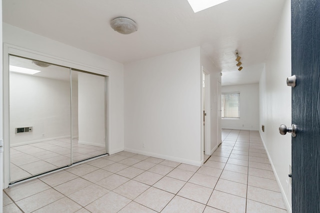 unfurnished bedroom featuring light tile patterned flooring, track lighting, a skylight, and a closet