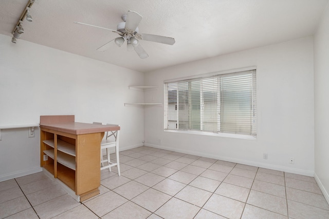 tiled spare room featuring track lighting, a textured ceiling, and ceiling fan