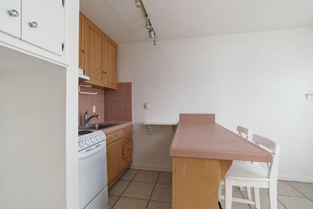 kitchen with tile countertops, sink, backsplash, light tile patterned floors, and white range with electric cooktop