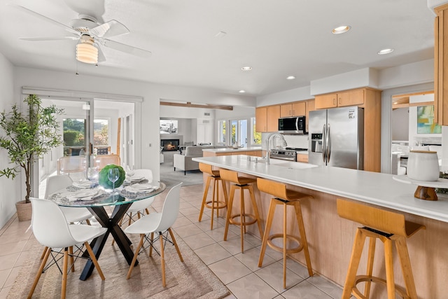 kitchen featuring ceiling fan, appliances with stainless steel finishes, light brown cabinetry, and light tile patterned floors