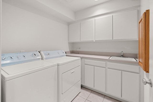 laundry room with cabinets, light tile patterned flooring, separate washer and dryer, and sink