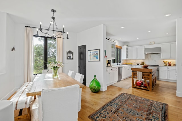 dining space featuring sink, a notable chandelier, and light hardwood / wood-style floors