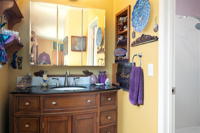 bathroom featuring tiled shower and vanity