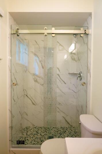 bathroom featuring a shower with shower door and toilet