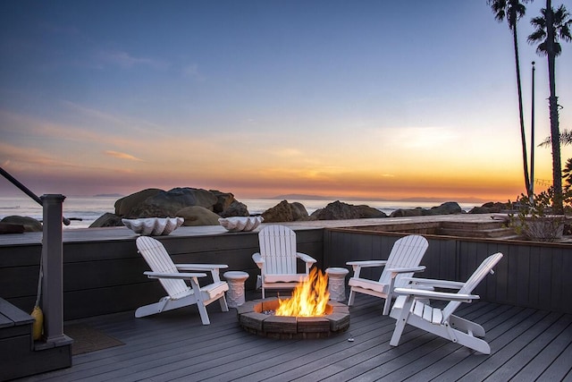 deck at dusk with a water view and an outdoor fire pit