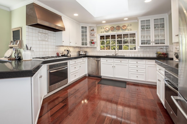 kitchen with white cabinetry, appliances with stainless steel finishes, sink, and wall chimney range hood