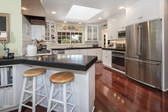 kitchen with sink, white cabinets, a kitchen bar, stainless steel appliances, and custom range hood