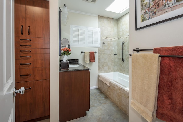 bathroom with tile patterned floors, crown molding, tiled shower / bath, a skylight, and vanity