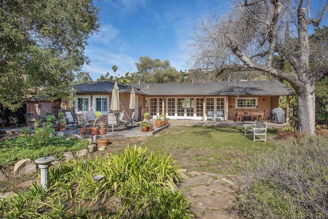 rear view of property with a patio and a lawn