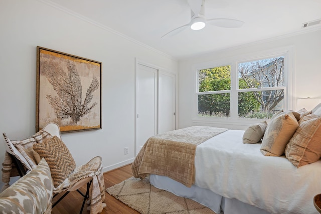 bedroom featuring crown molding, hardwood / wood-style floors, ceiling fan, and a closet