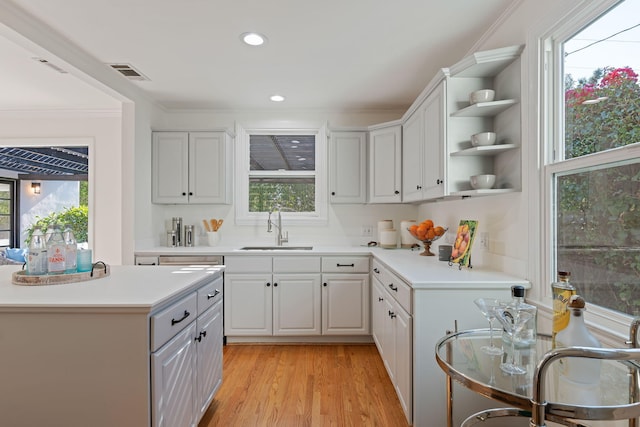 kitchen featuring white cabinetry, ornamental molding, sink, and light wood-type flooring