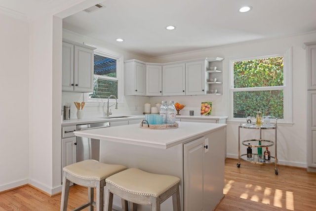 kitchen with light hardwood / wood-style flooring, stainless steel dishwasher, a healthy amount of sunlight, and a kitchen island