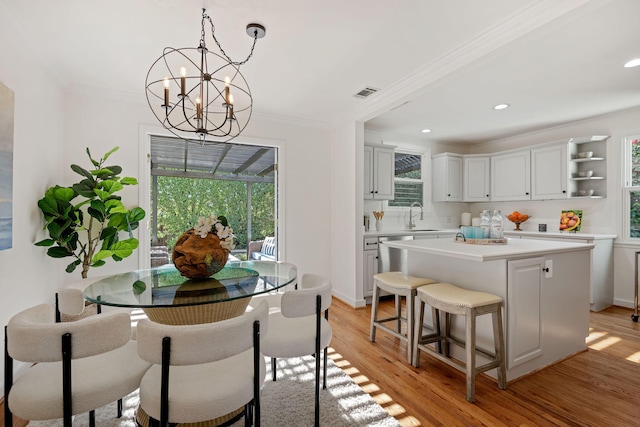 dining area featuring a wealth of natural light, ornamental molding, and light wood-type flooring