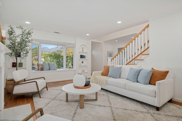 living room with built in shelves, ornamental molding, and hardwood / wood-style floors