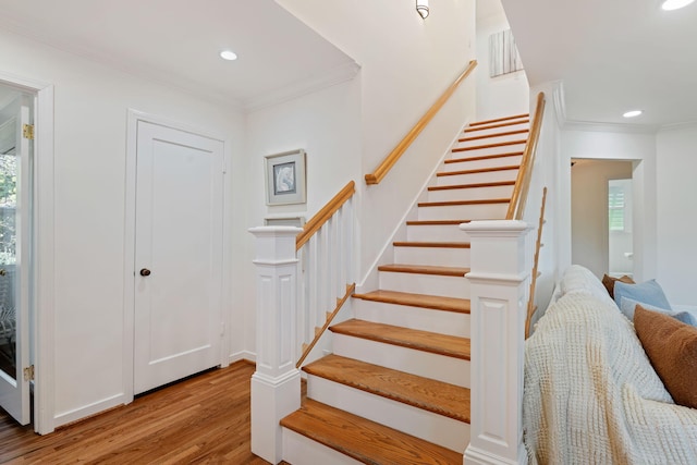 staircase with ornamental molding and hardwood / wood-style floors