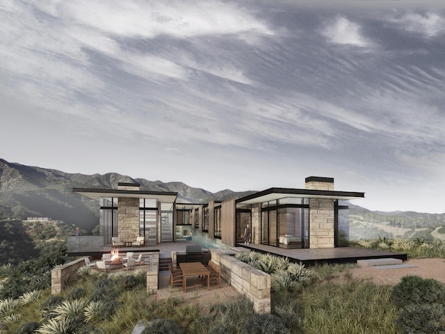 rear view of property featuring a gazebo, a mountain view, and an outdoor fire pit