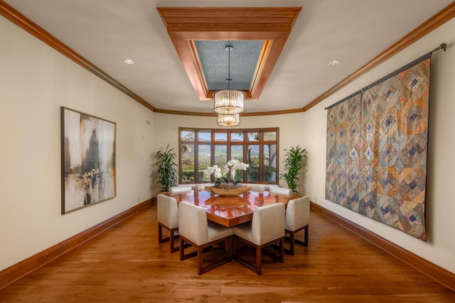 dining area featuring crown molding, a notable chandelier, a tray ceiling, and wood-type flooring